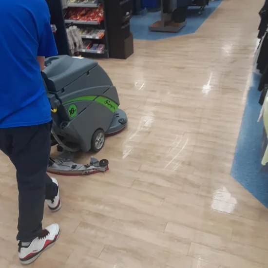 A man operates a floor cleaning machine in a retail store, efficiently maintaining cleanliness in the aisles.
