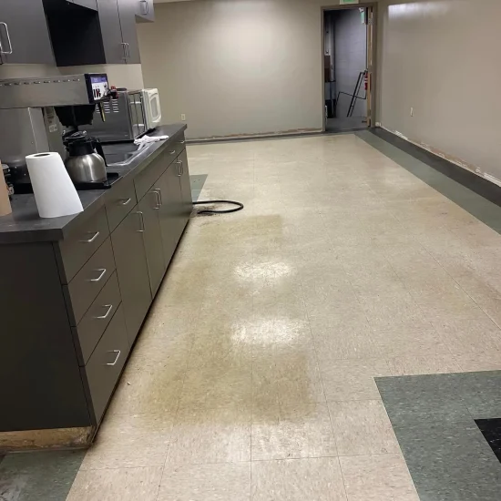 A yellow cleaning machine operates on a checkered floor, effectively removing dirt and debris.